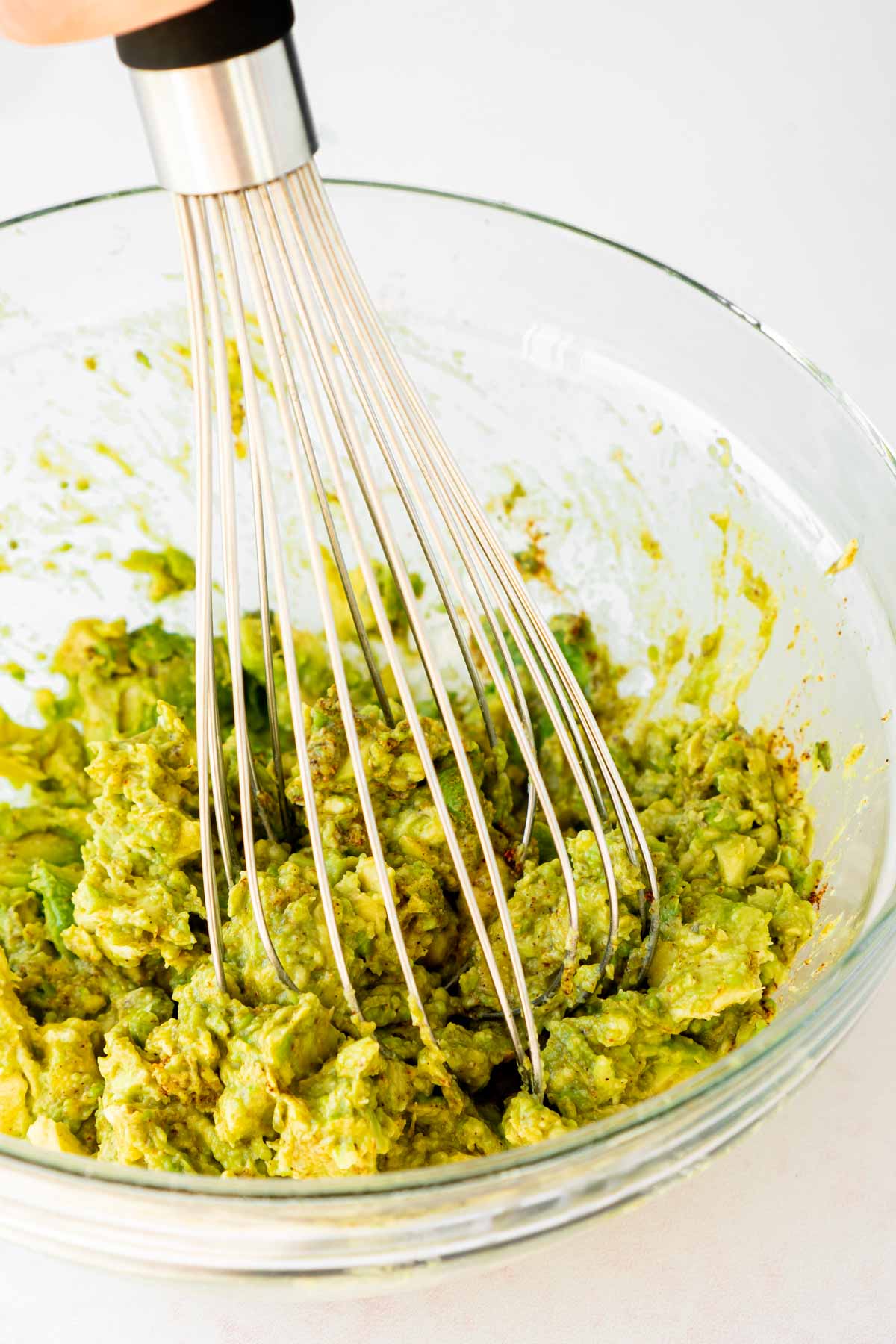 Avocado being mashed with a whisk