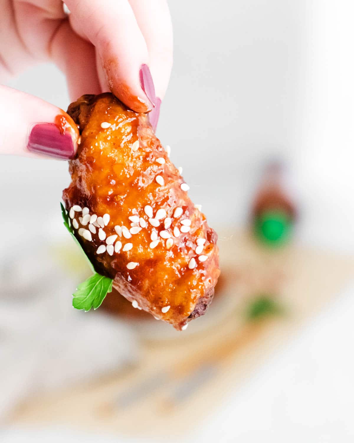 Woman's hand holding a sticky Asian chicken wing