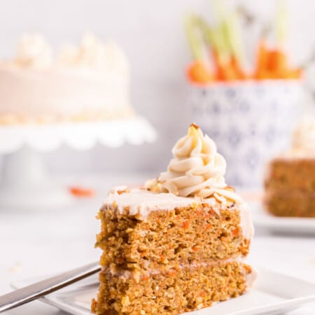 A slice of carrot cake with a dollop of cream cheese frosting on top