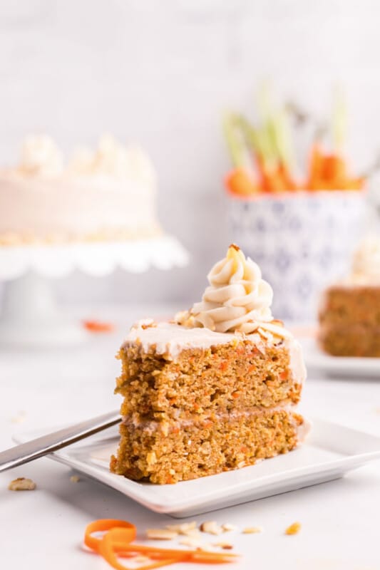 A slice of carrot cake with a dollop of cream cheese frosting on top