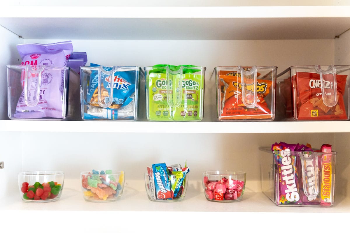 Snacks in clear plastic buckets in a cabinet