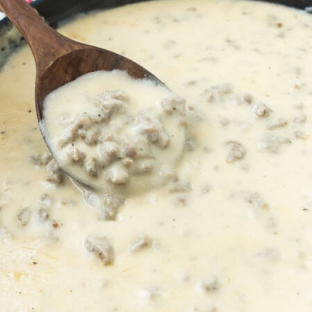 Pan of sausage gravy with a wood spoon