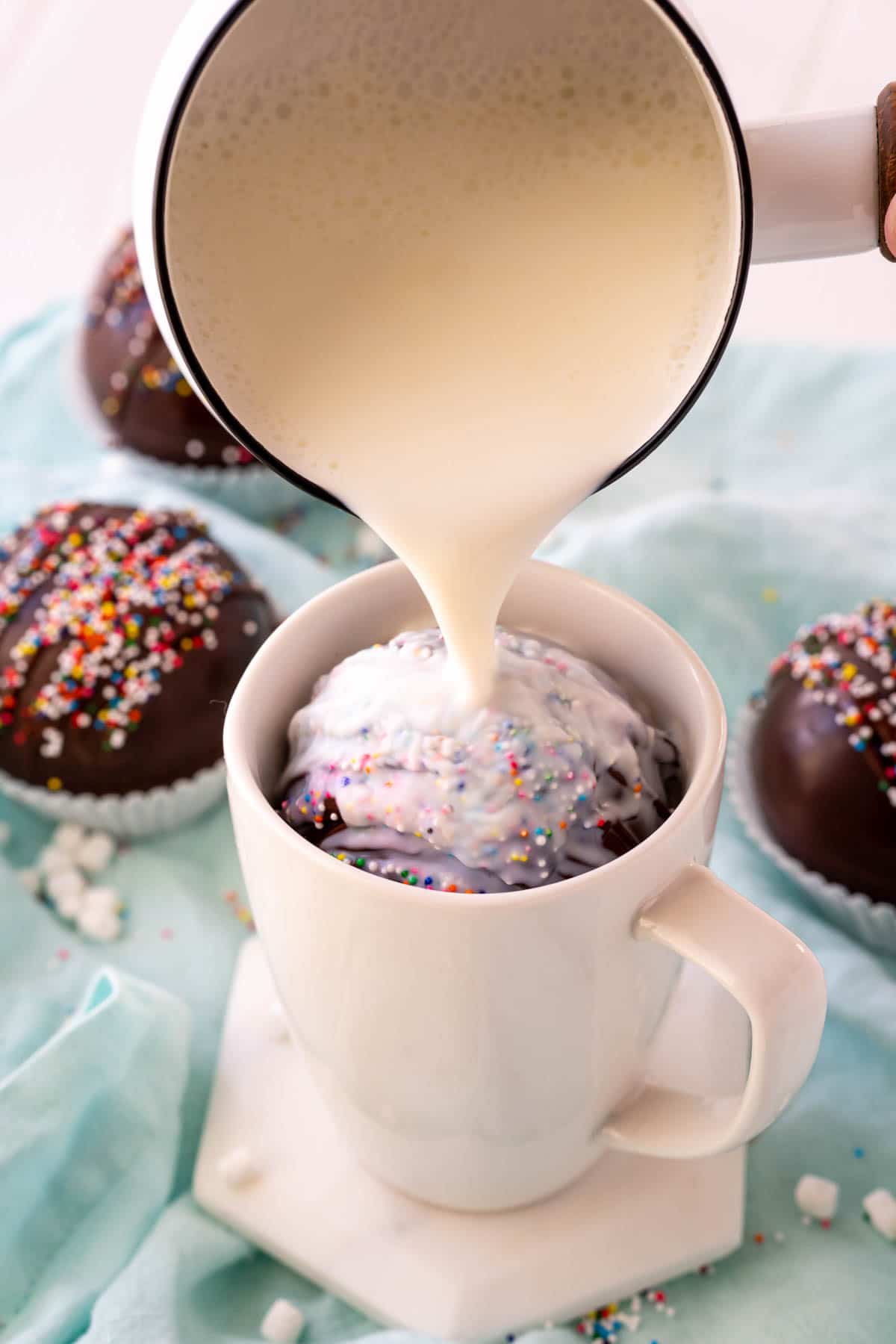 Milk being poured over a hot chocolate bomb in a mug
