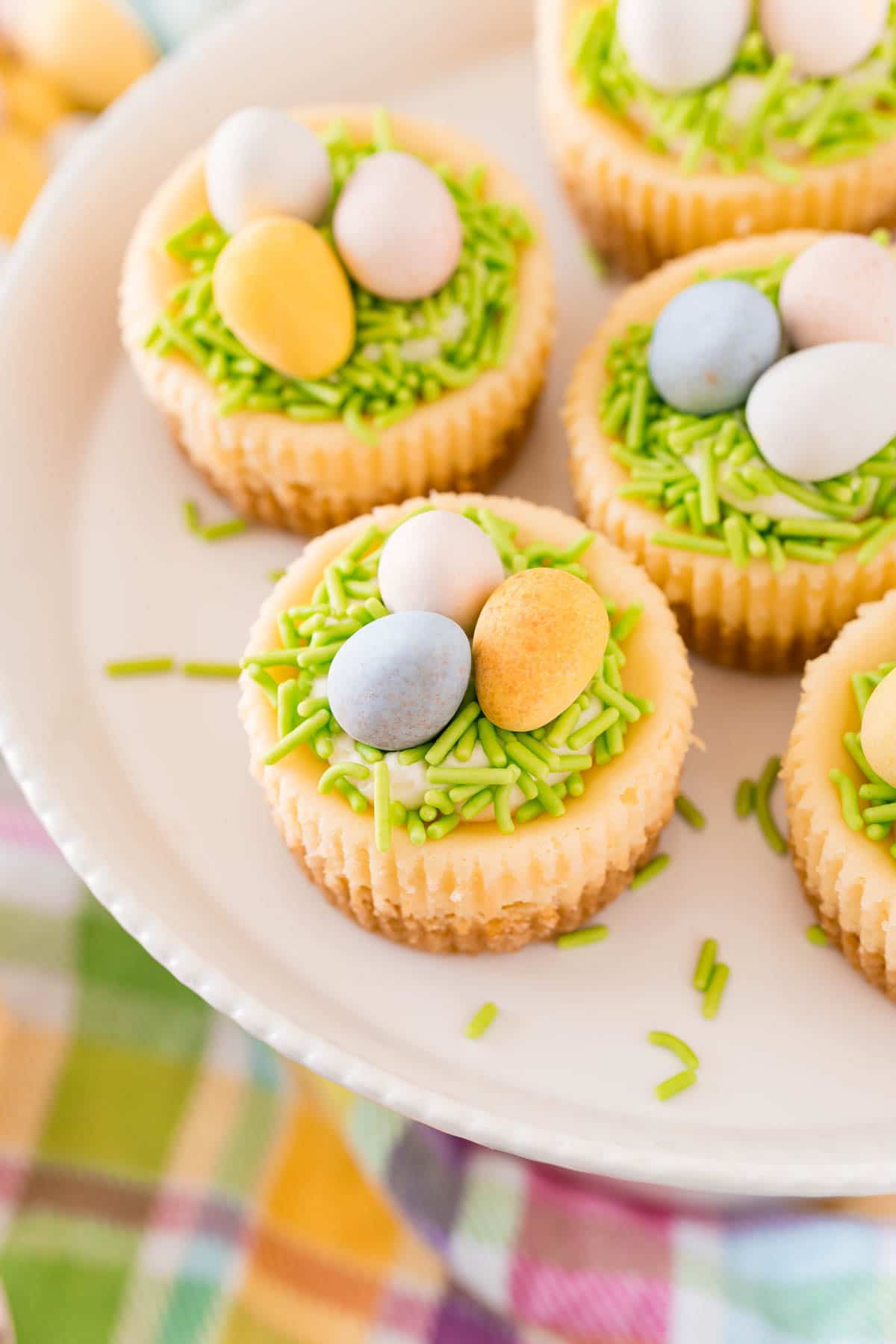 white cake stand full of mini egg cheesecakes