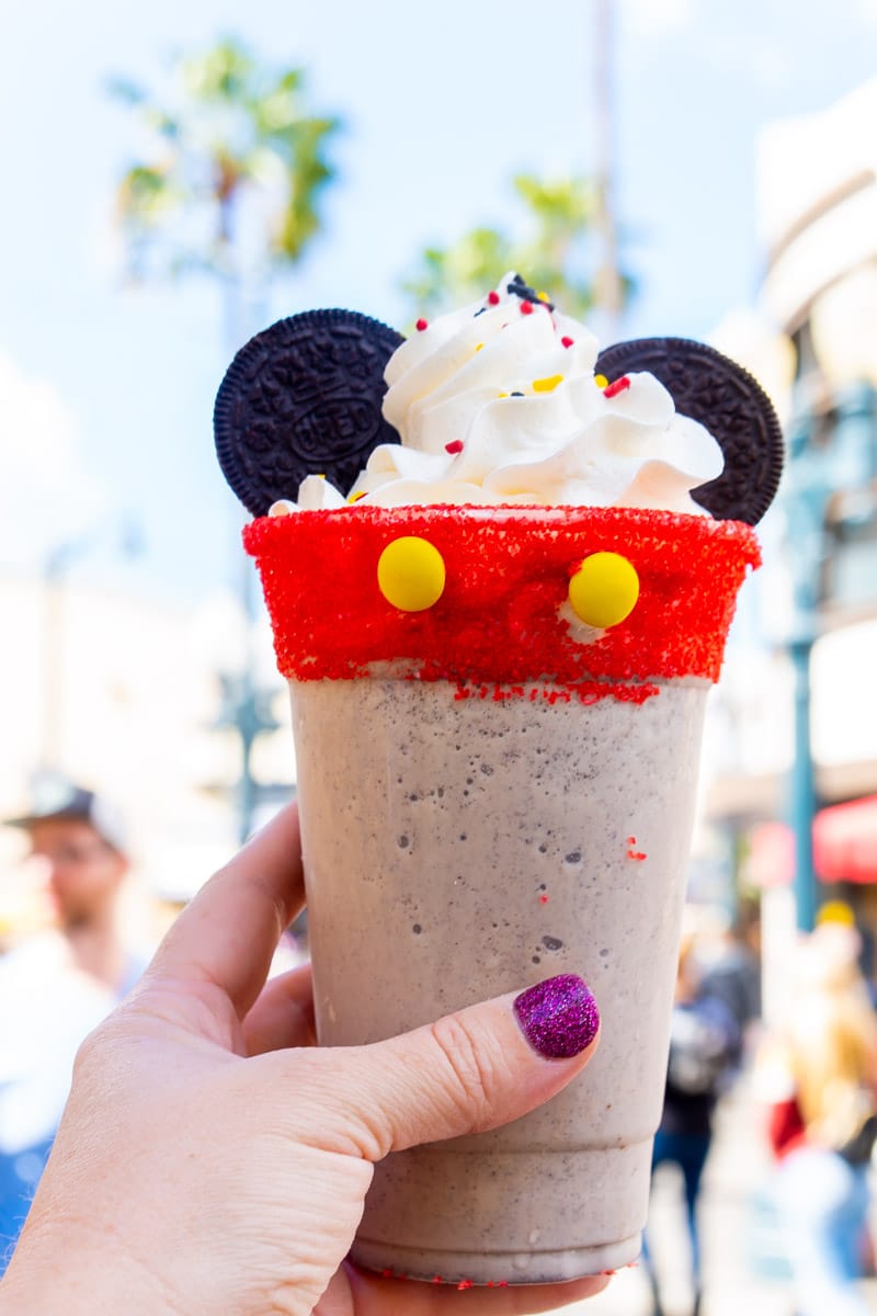 Hand holding a Mickey Mouse milkshake