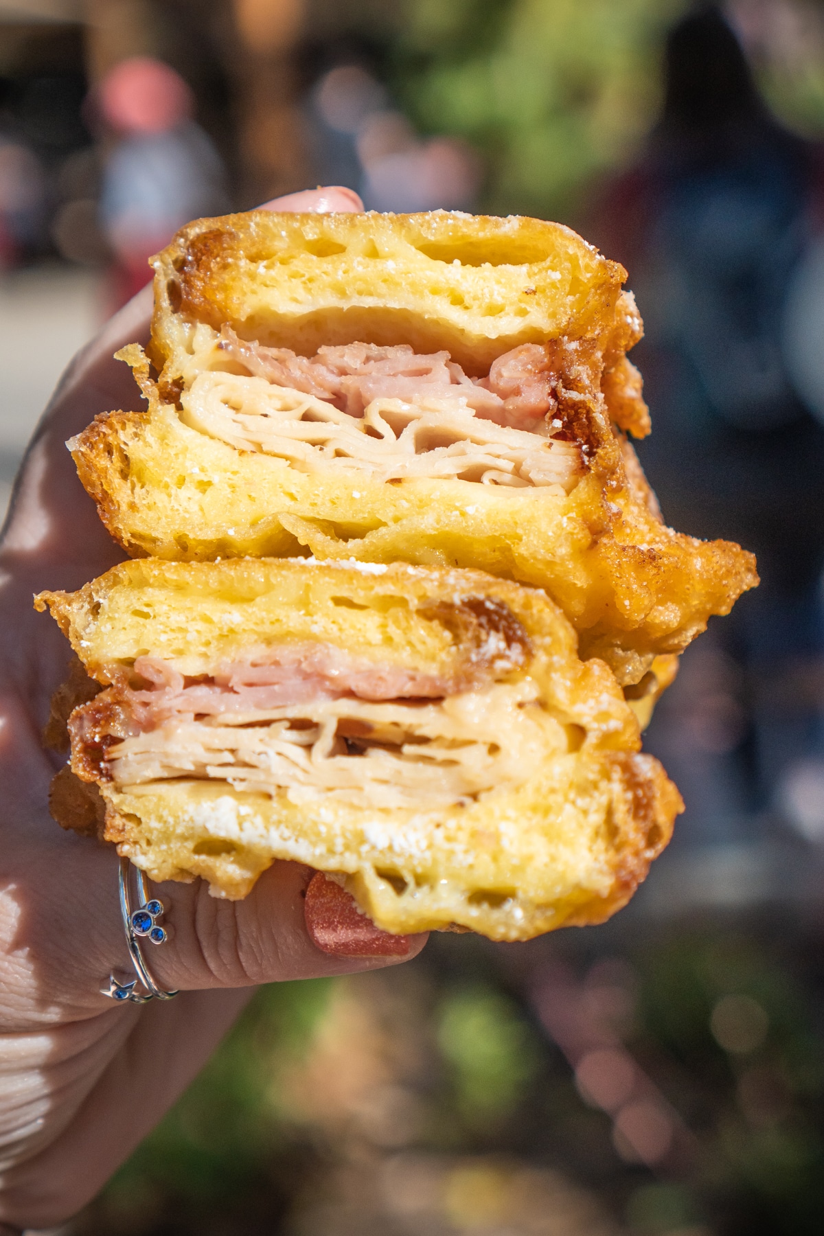 someone's hand holding a monte cristo sandwich at Disneyland