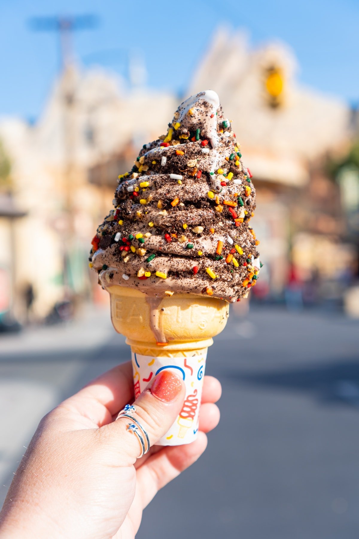 Hand holding an ice cream cone with junkyard topping