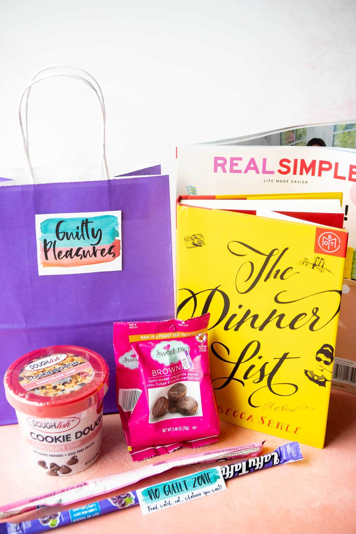 purple gift bag with a book and magazine aroun