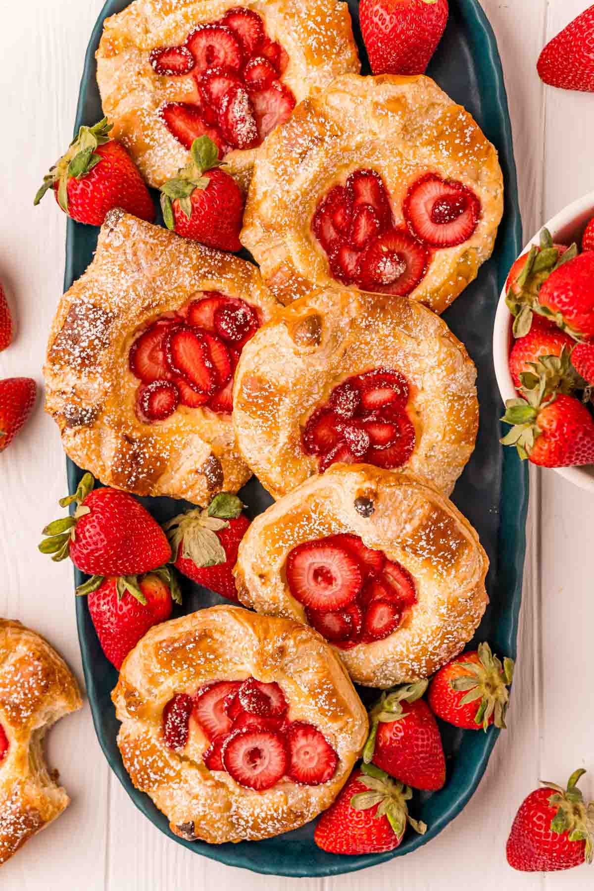 plate full of strawberry danishes with strawberries around