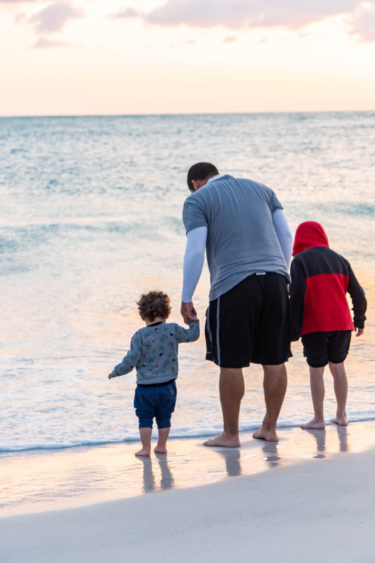 Dad and two boys holding hands on the beach