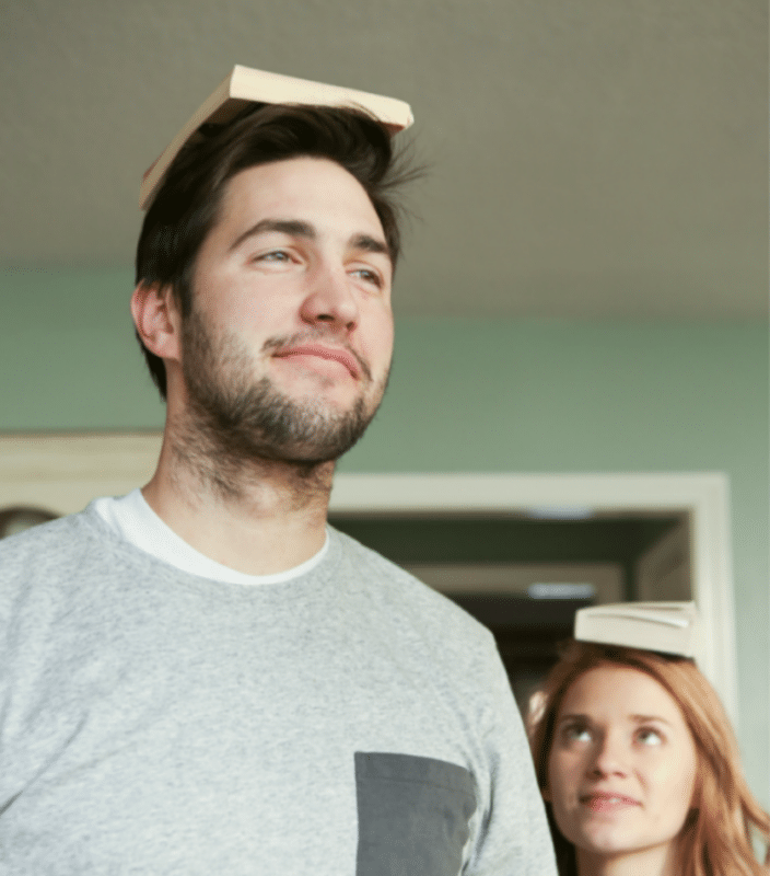 girl and boy walking with a book on their head