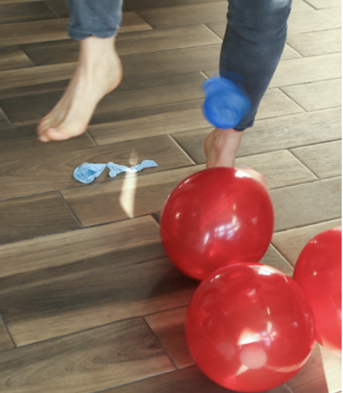 foot trying to pop red balloons