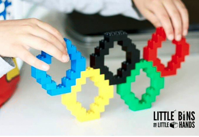 Hand holding Olympics rings made out of Legos