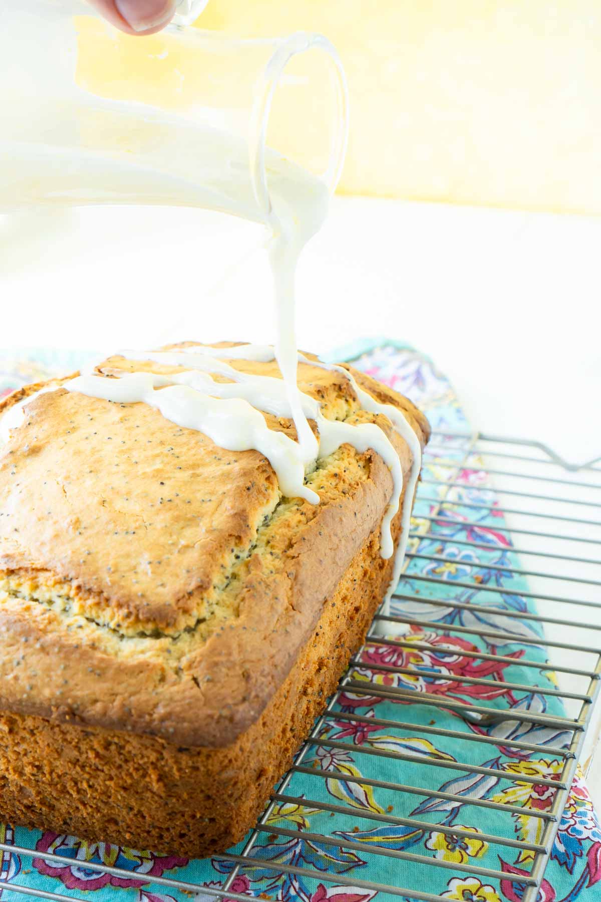 jar pouring glaze on lemon poppy seed bread