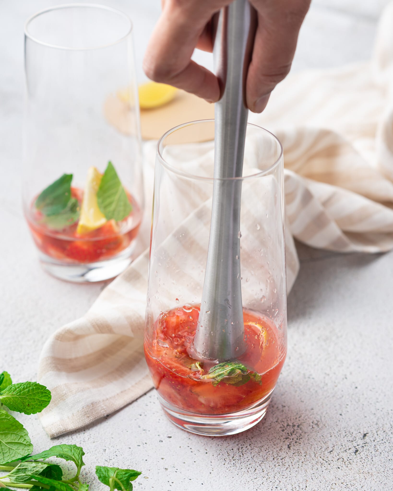 Metal muddler in a glass with strawberry mixture