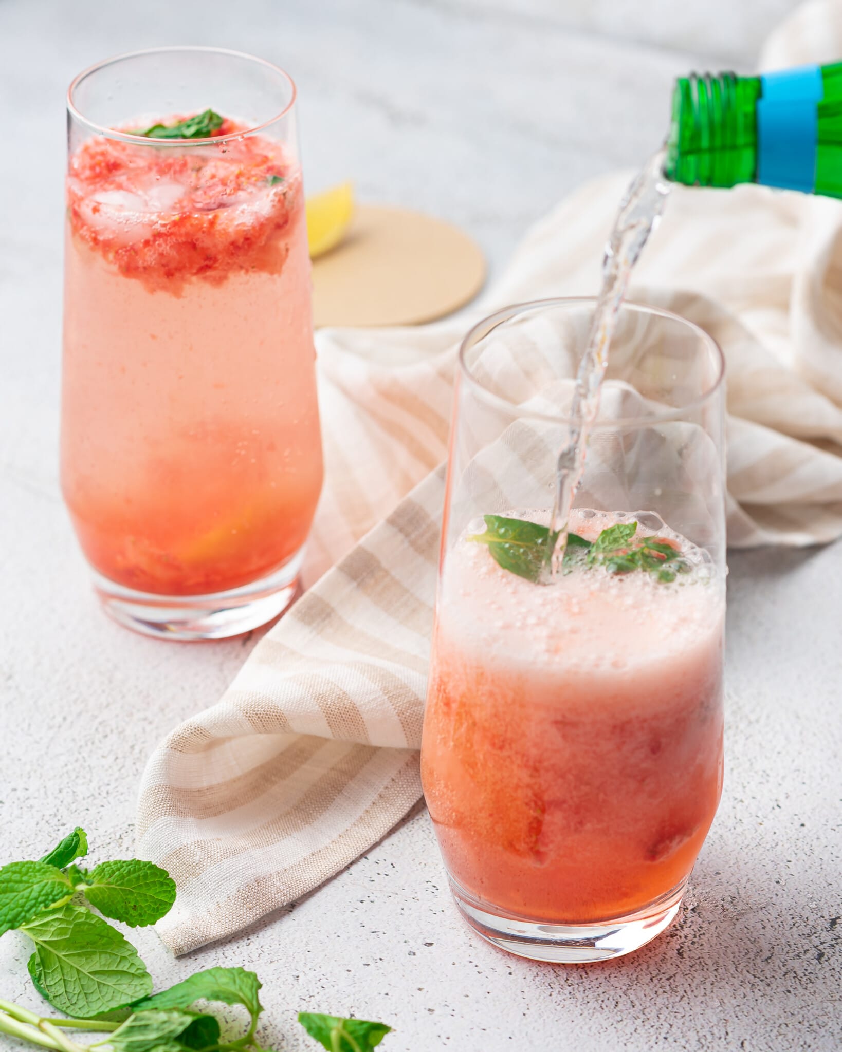Pouring sparkling water into a strawberry mocktail mojito glass