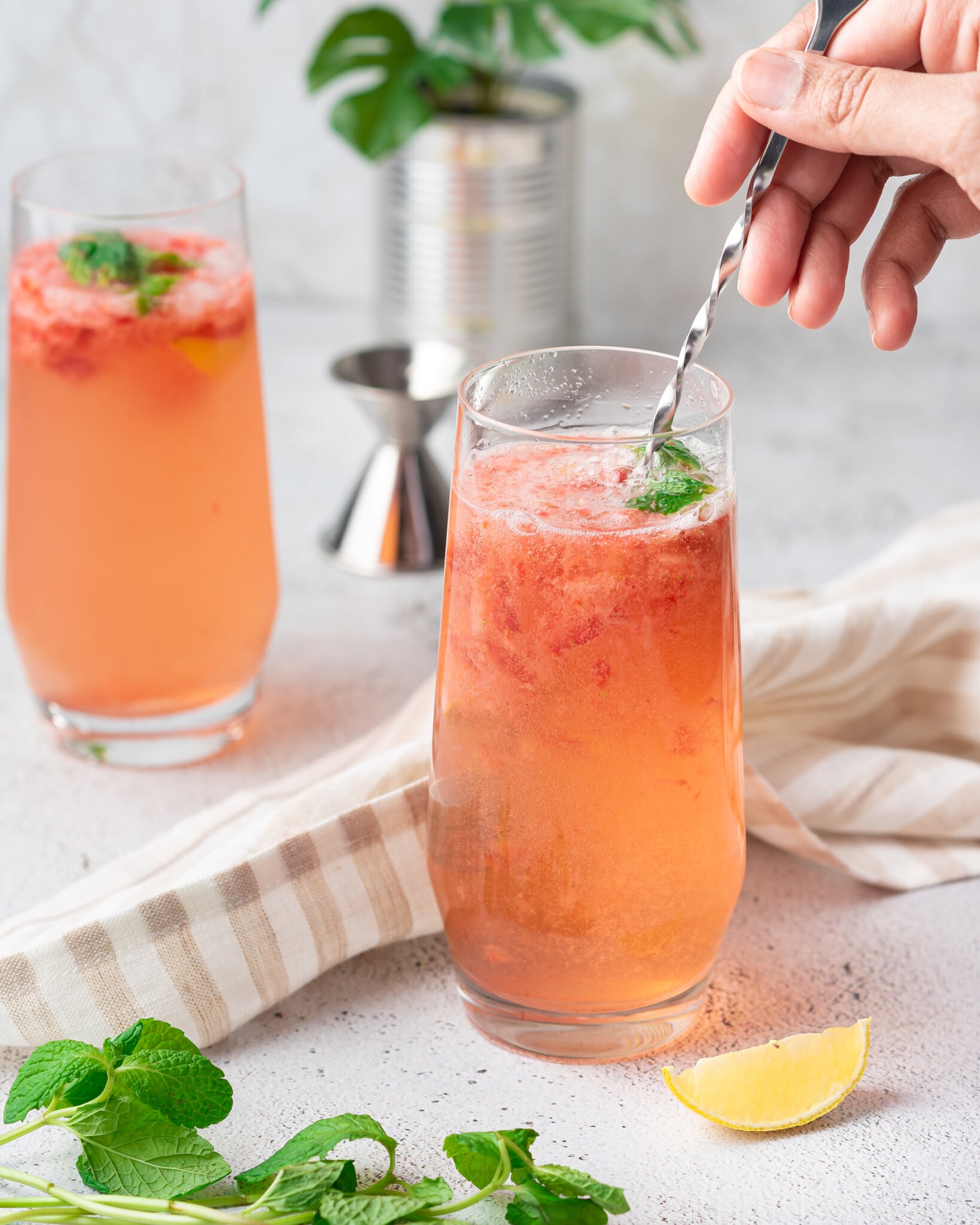 Woman's hand stirring a strawberry mojito