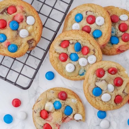 chocolate chip M&M cookies on and next to a wire cooling rack