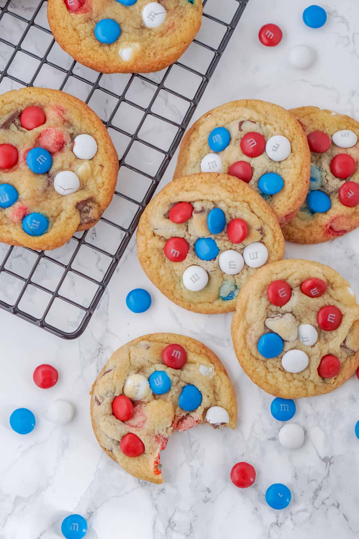 chocolate chip M&M cookies on and next to a wire cooling rack