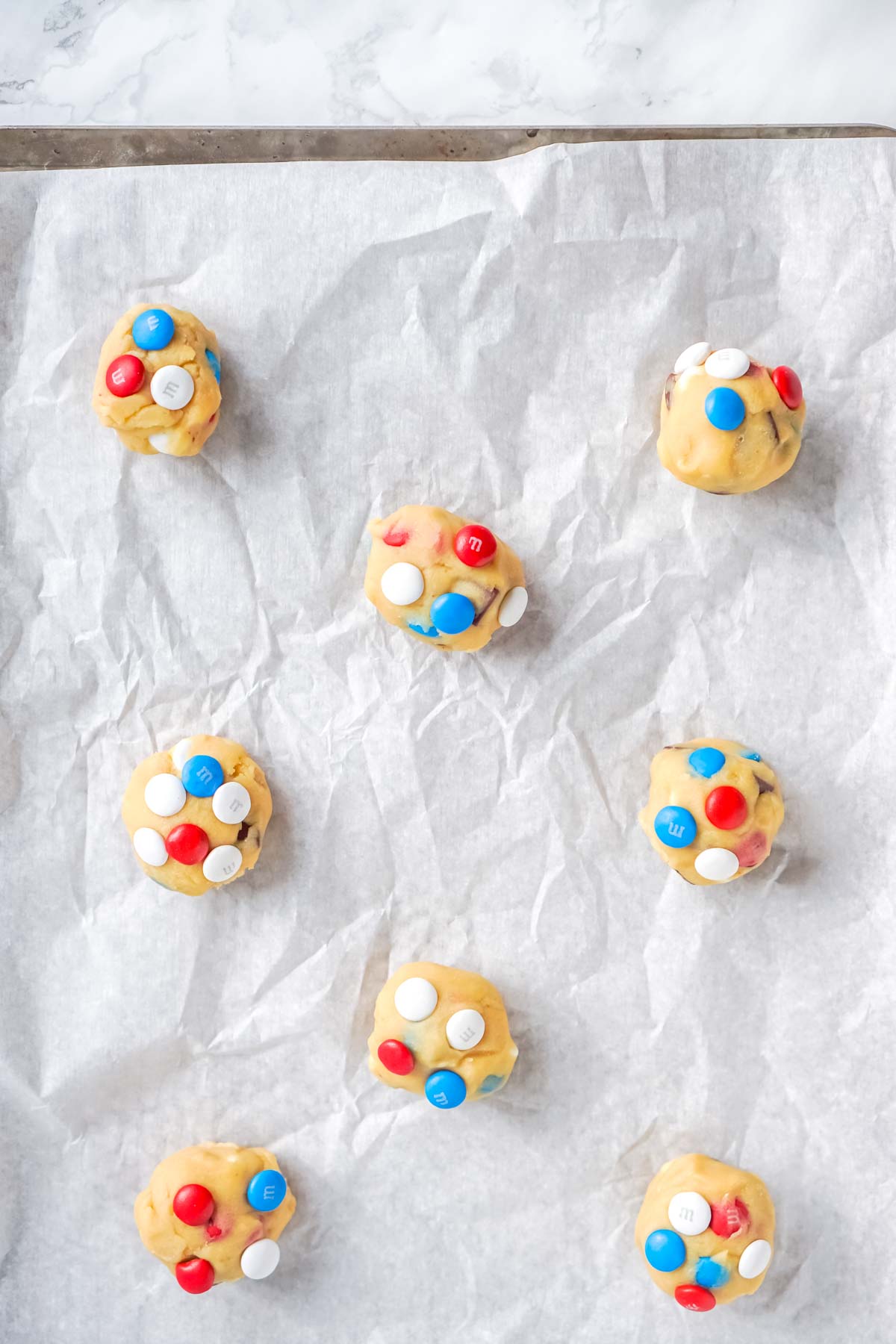 unbaked chocolate chip M&M cookies on a baking sheet