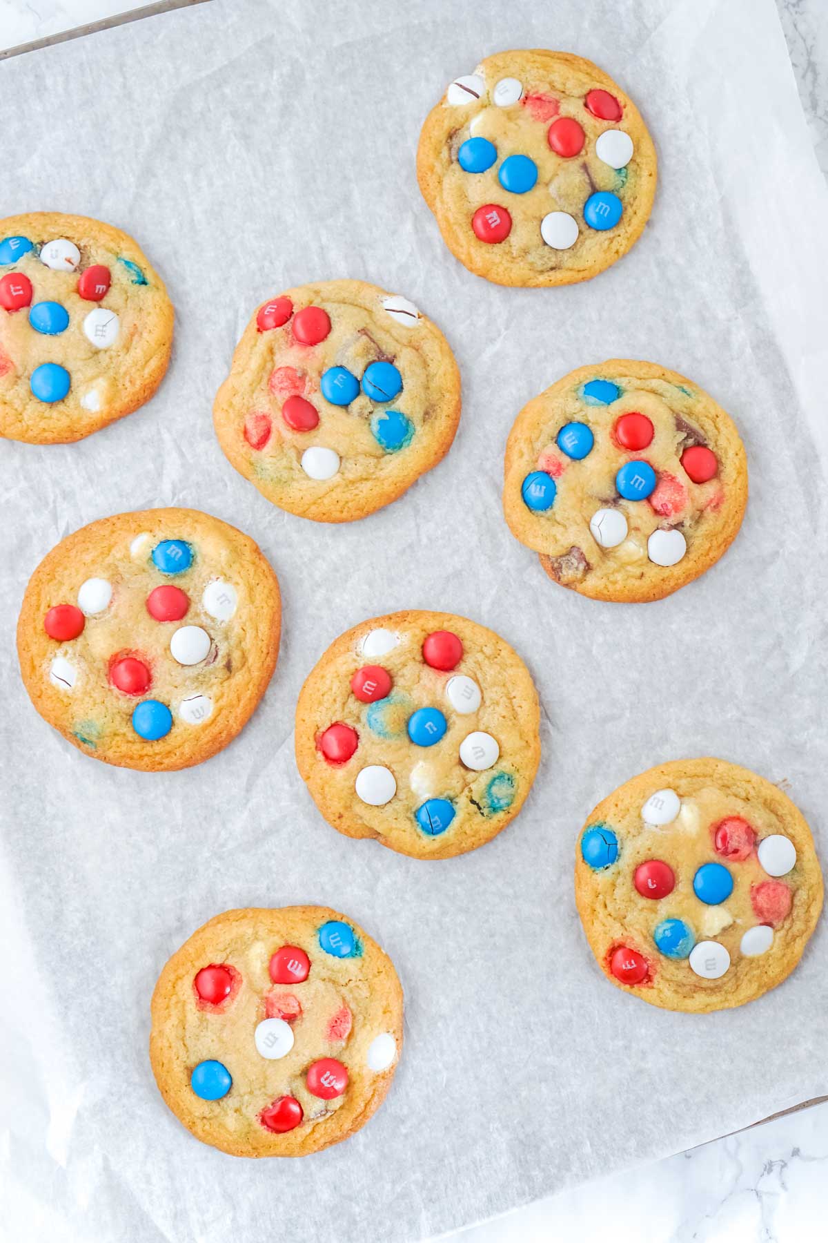 chocolate chip M&M cookies cooling on a piece of parchment paper