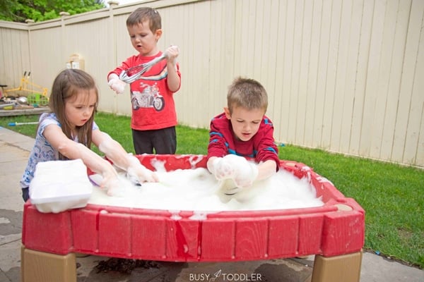 kids playing at a water table filled with foam