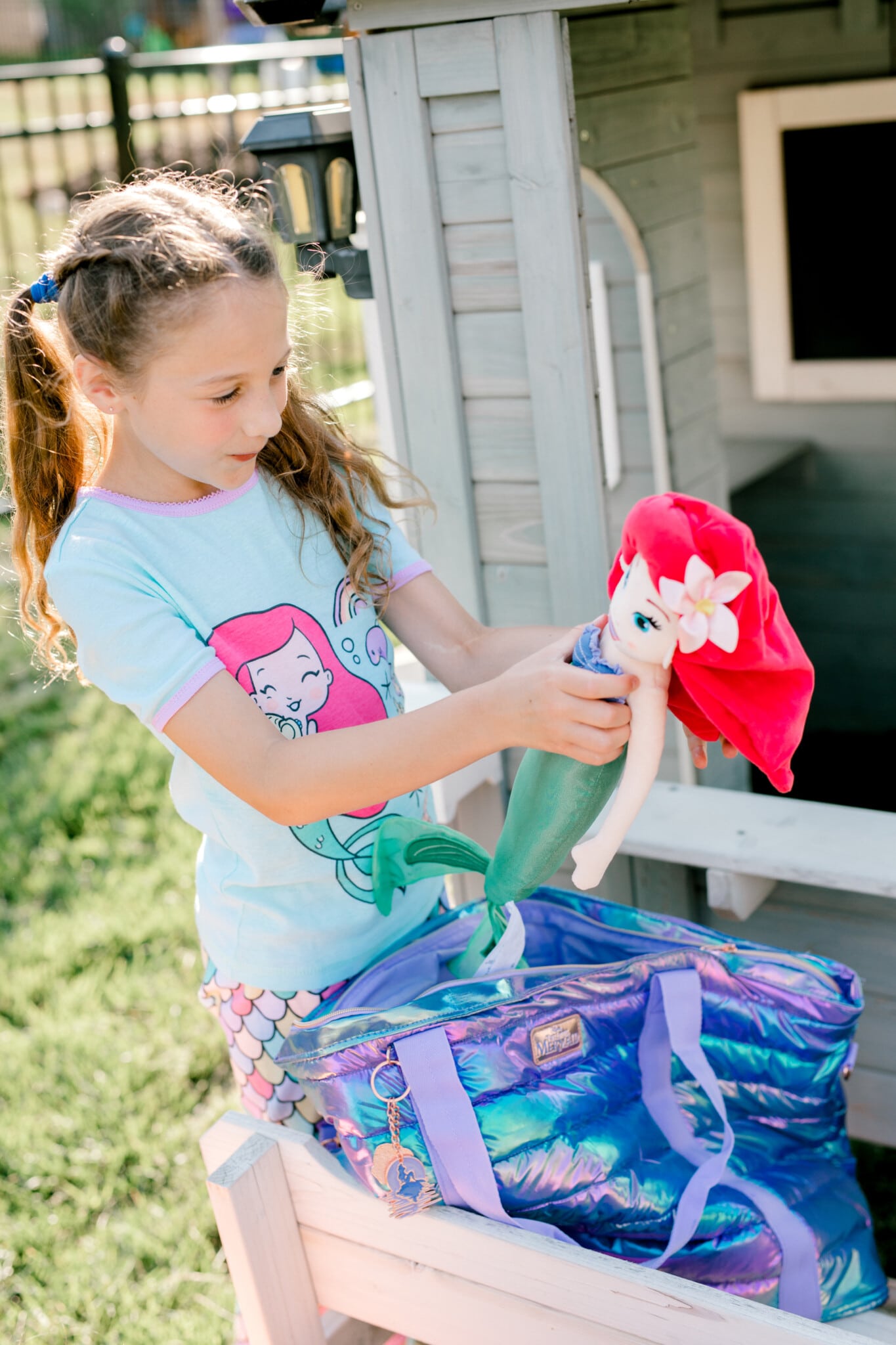 girl holding a plush Ariel doll