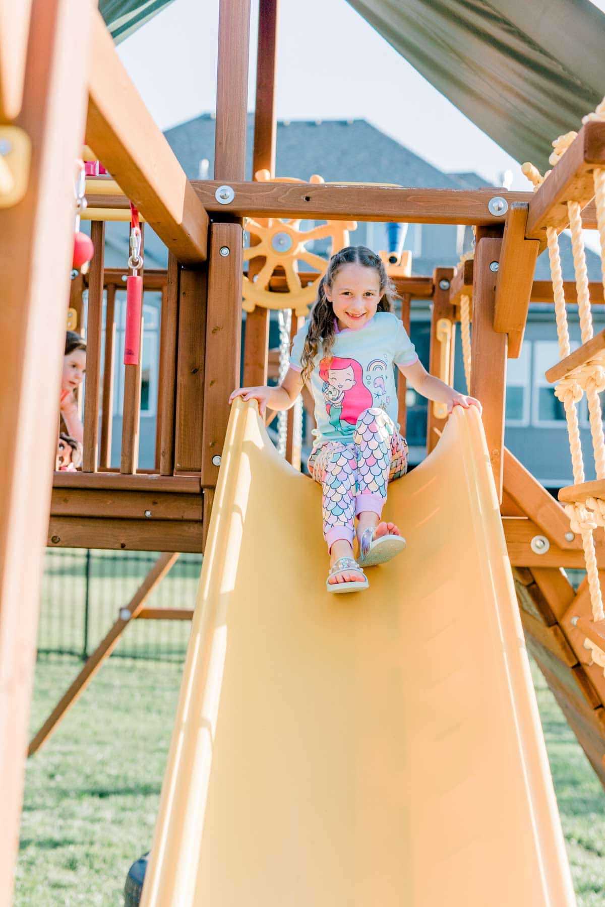 girl in Ariel pajamas going down the slide