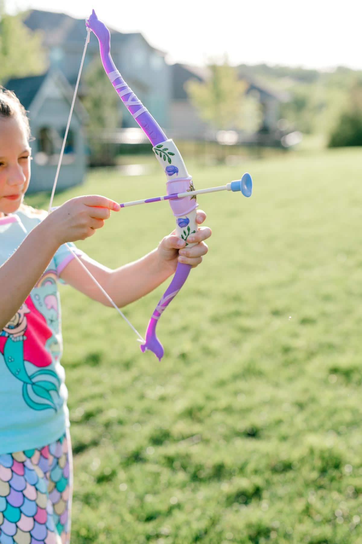 girl holding a purple Rapunzel bow and arrow set