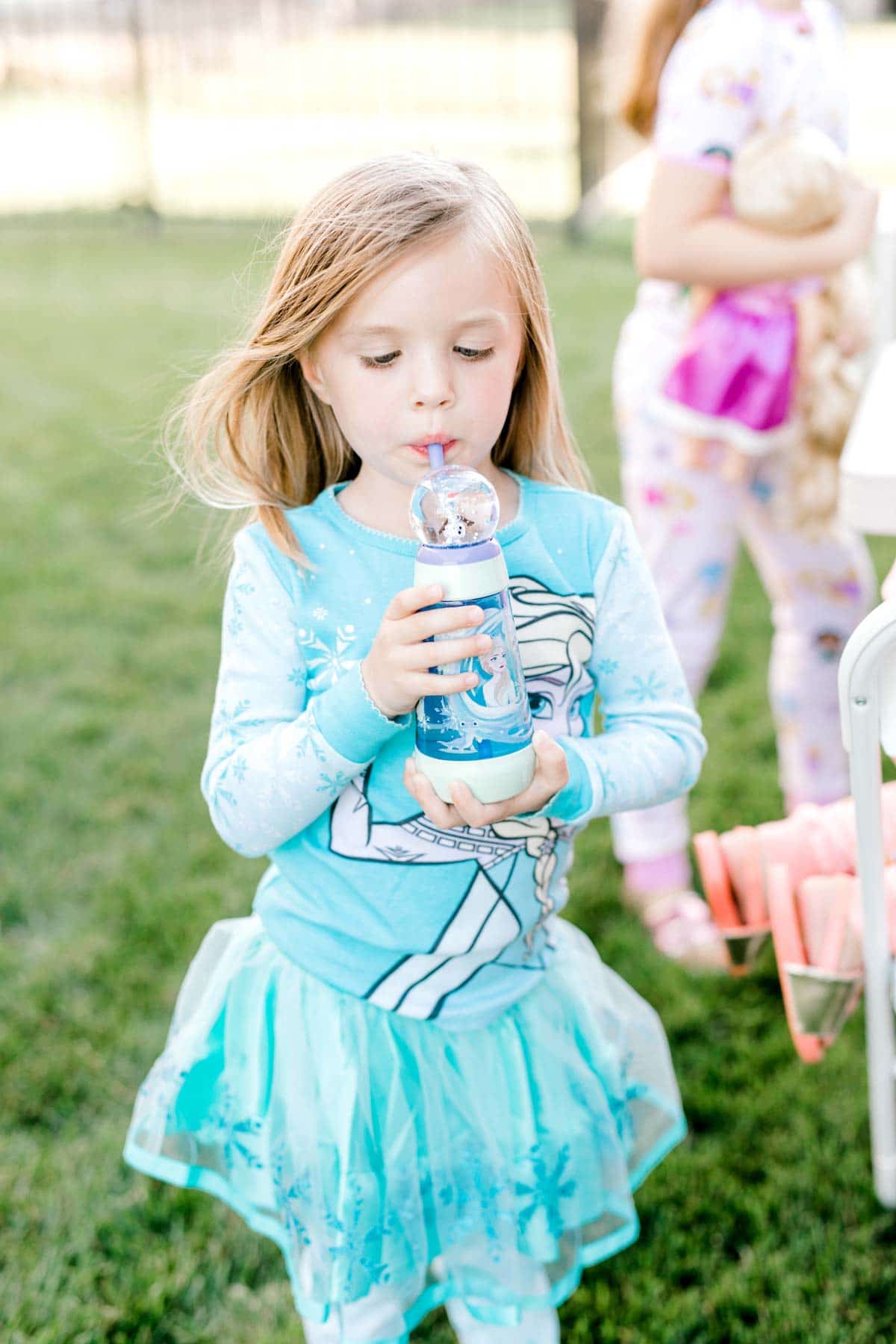 girl dressed in an elsa outfit with a water bottle