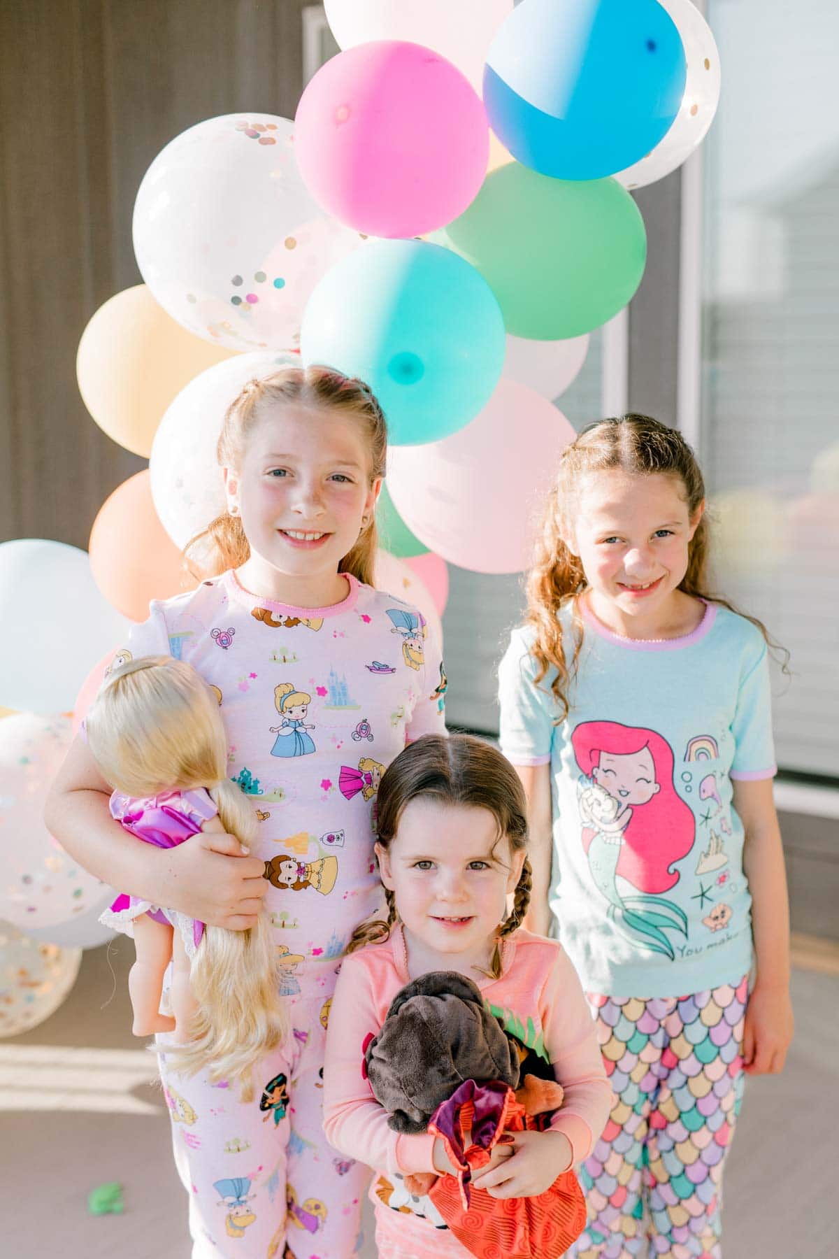 three girls standing in front of a balloon garland