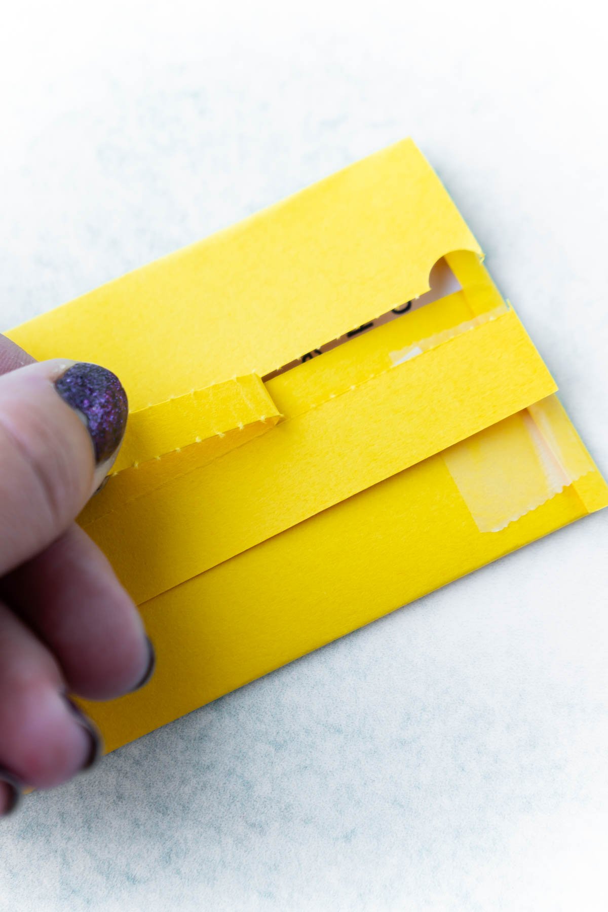 Hand pulling a tear strip on an Amazing Race envelope