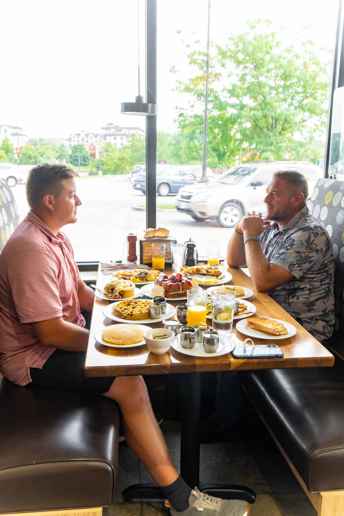 Two men sitting at a table with breakfast food