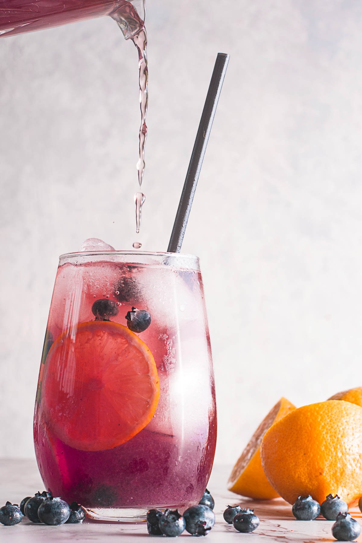 pouring water into a blueberry lemonade glass