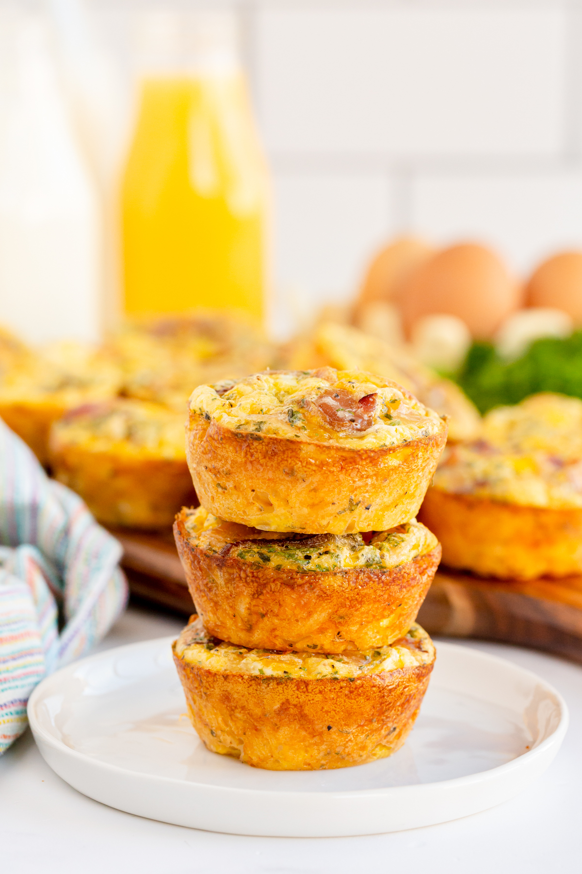 three stacked breakfast muffins on a white plate