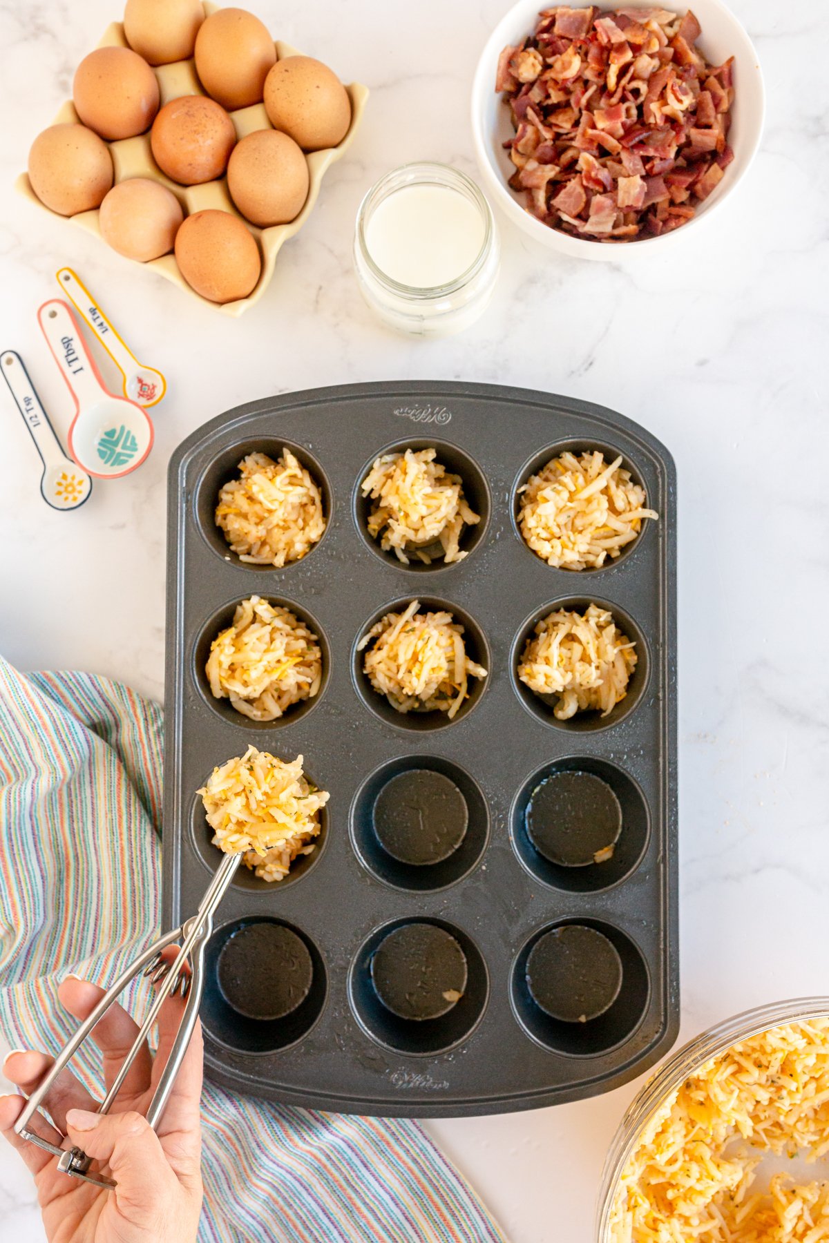 hand putting hash browns in muffin tins