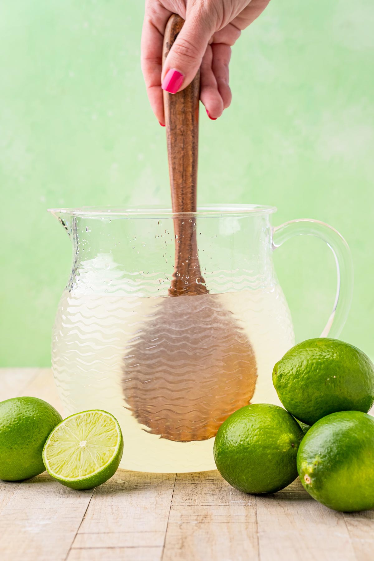 stirring a glass pitcher of limeade