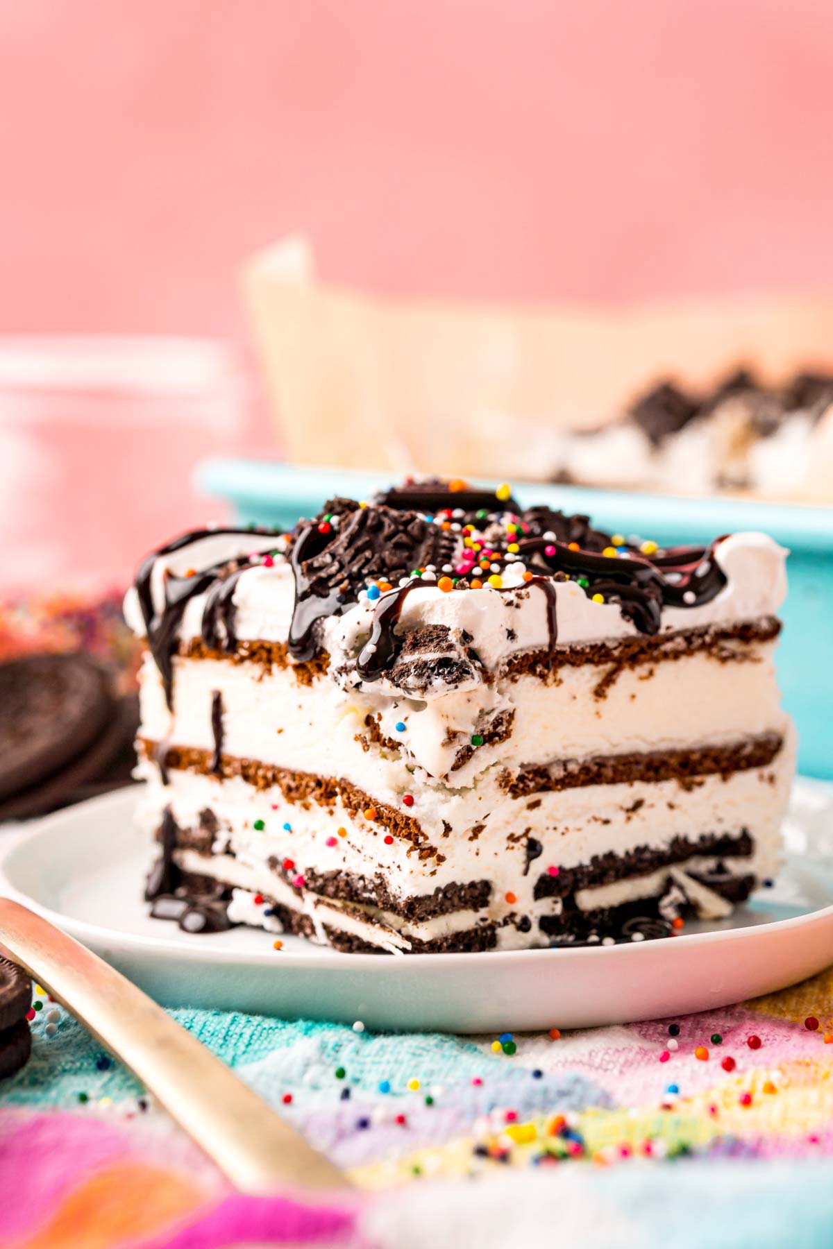 A slice of oreo ice cream cake with a pink background