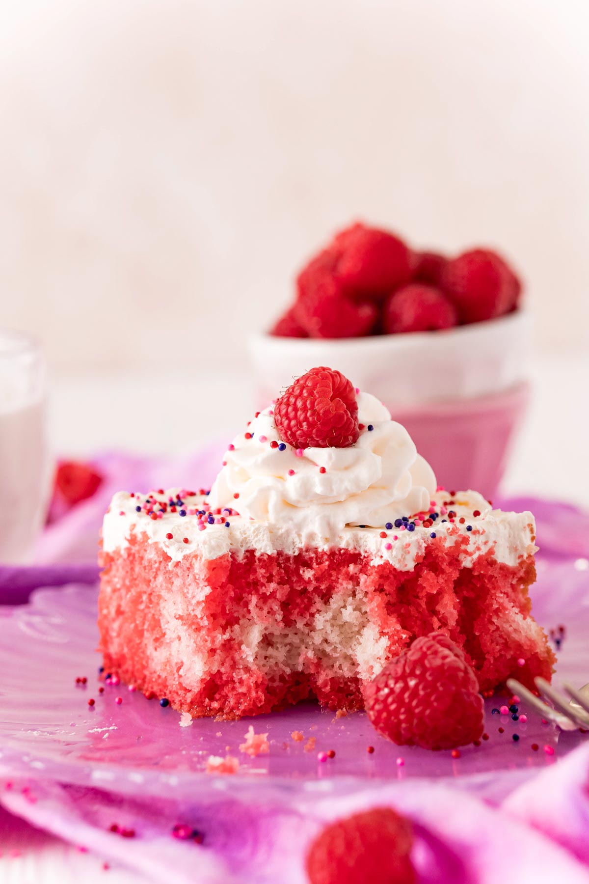 slice of raspberry jello poke cake with a bite out of it