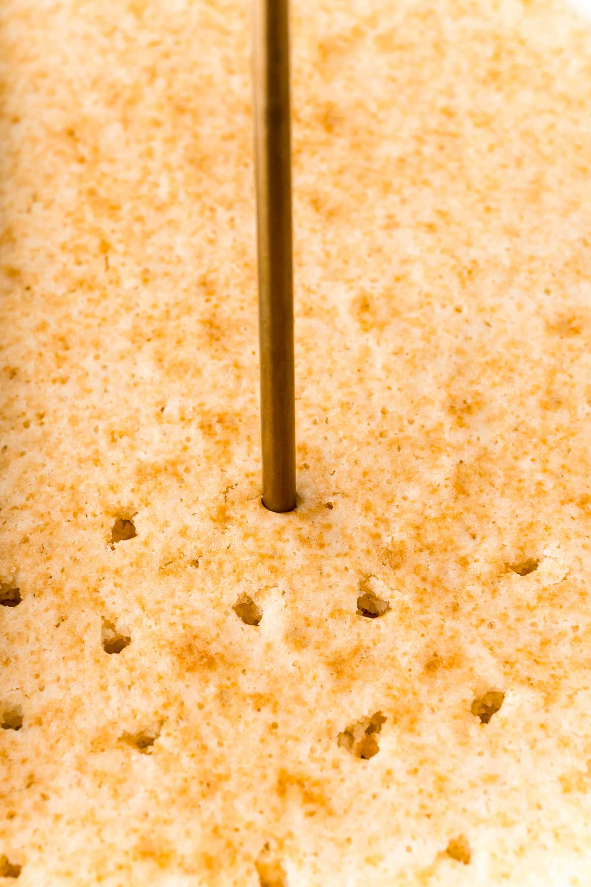 wooden skewer putting holes in the top of a cake