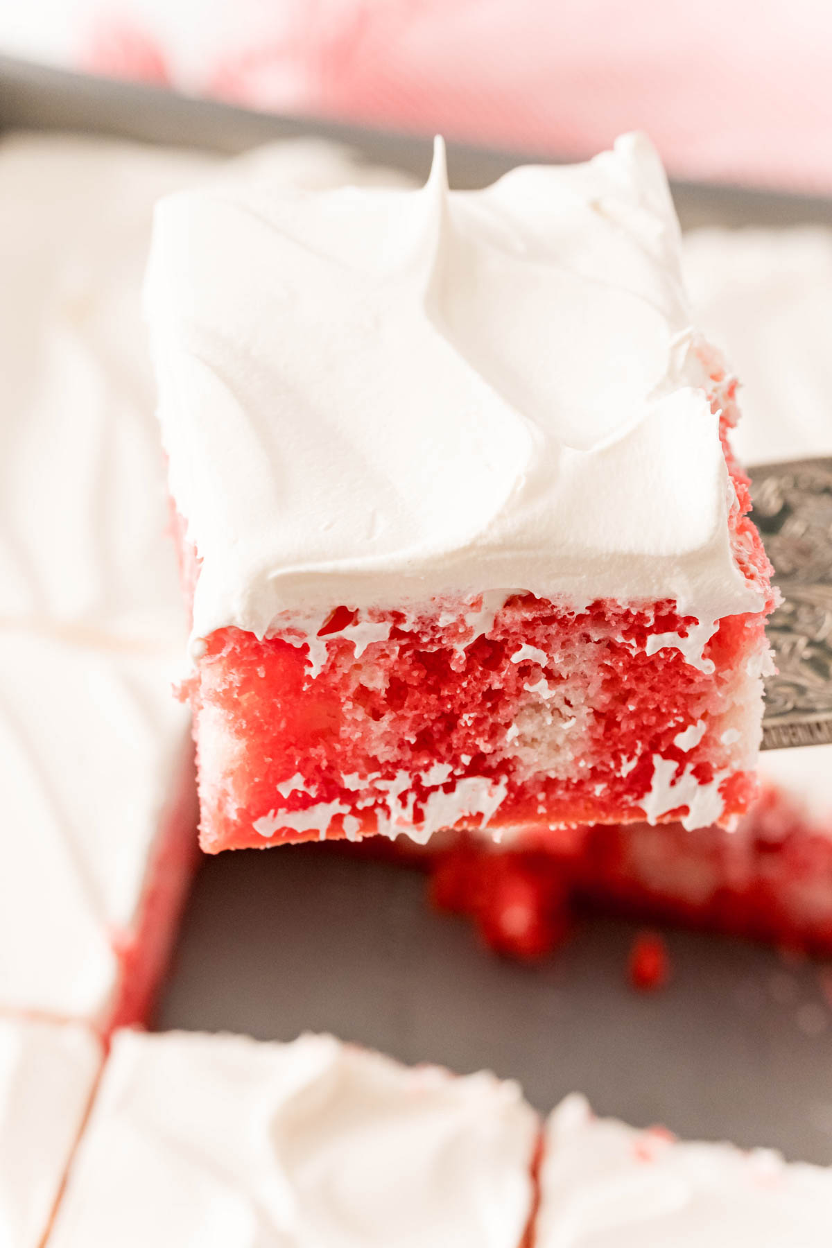 slice of raspberry jello poke cake with whipped topping