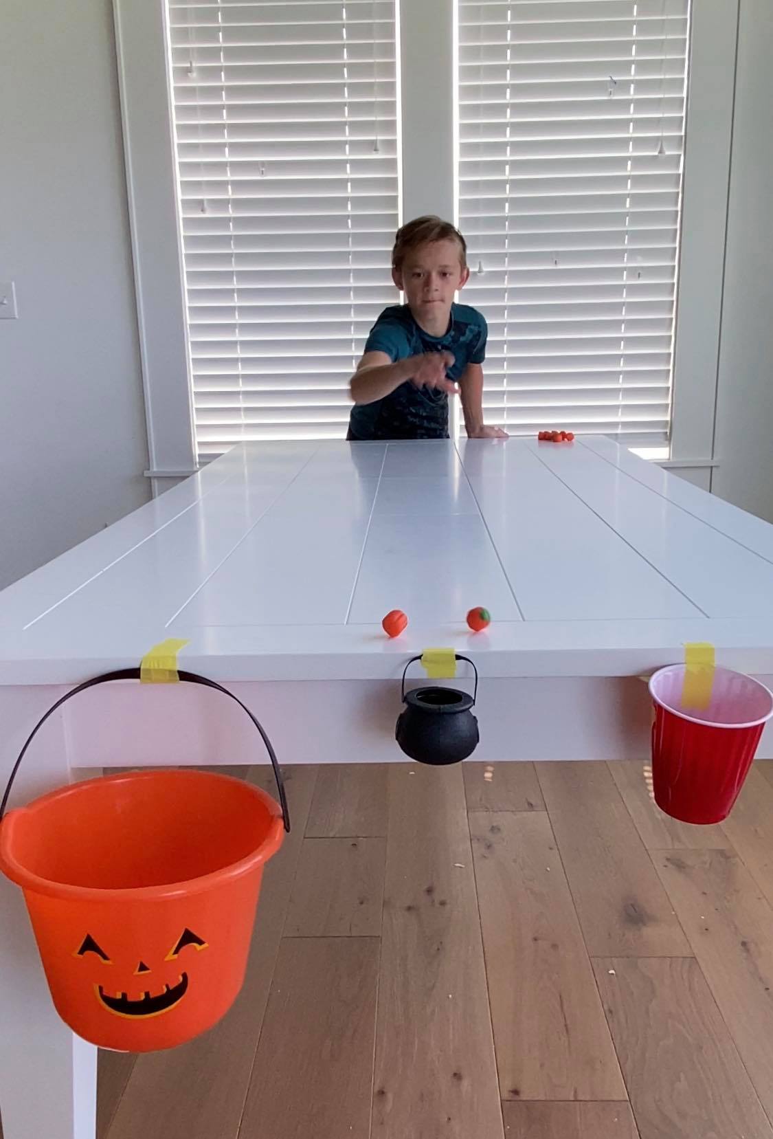 Kid sliding pumpkins across a table