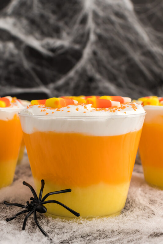candy corn layered pudding dessert with a plastic spider