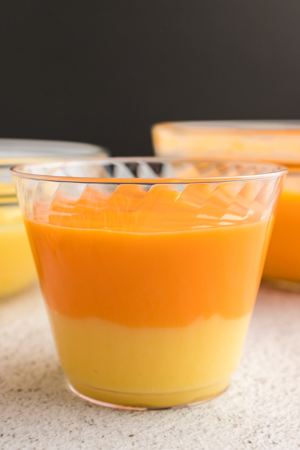 yellow and orange pudding in a plastic cup