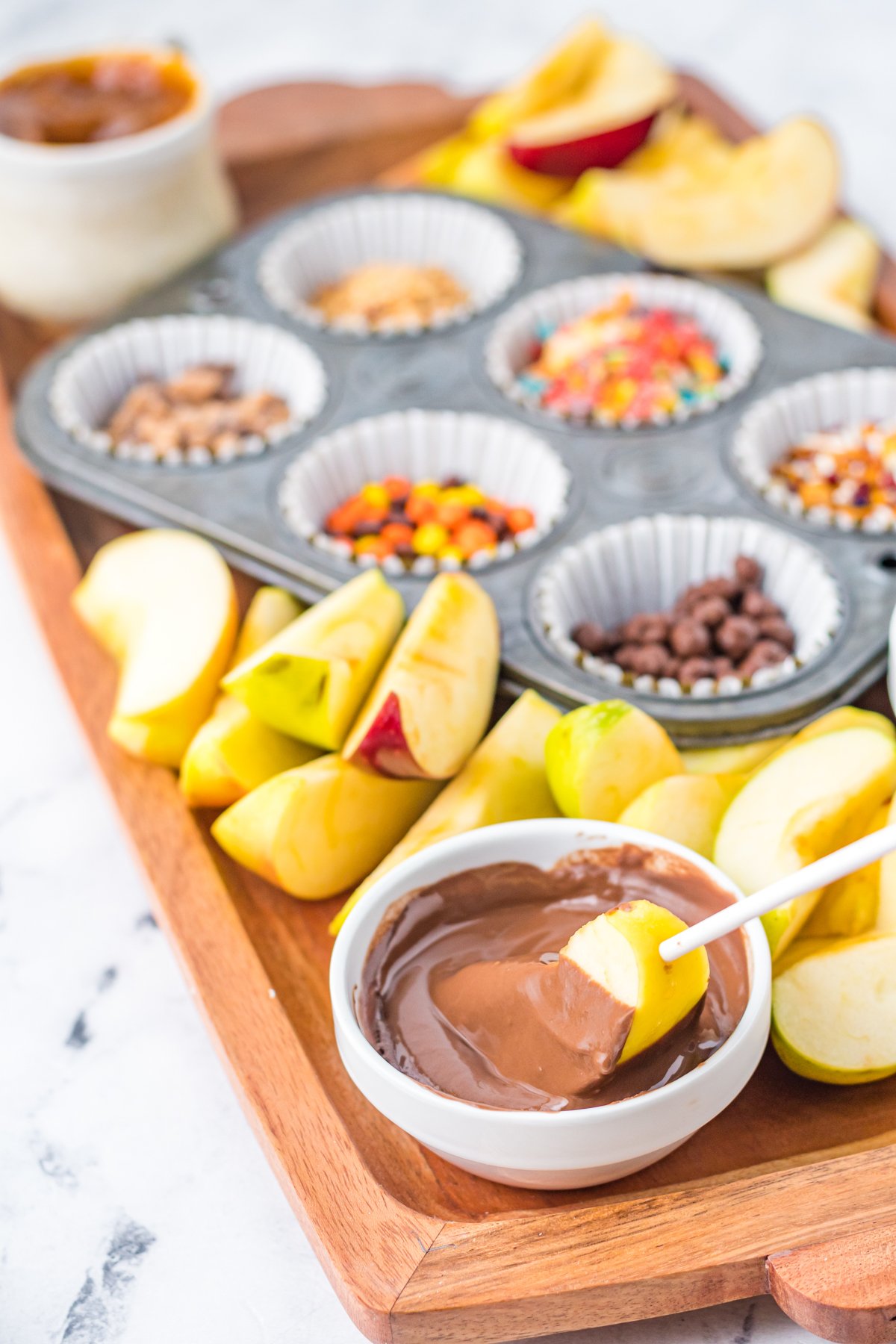 apple being dipped into melted chocolate