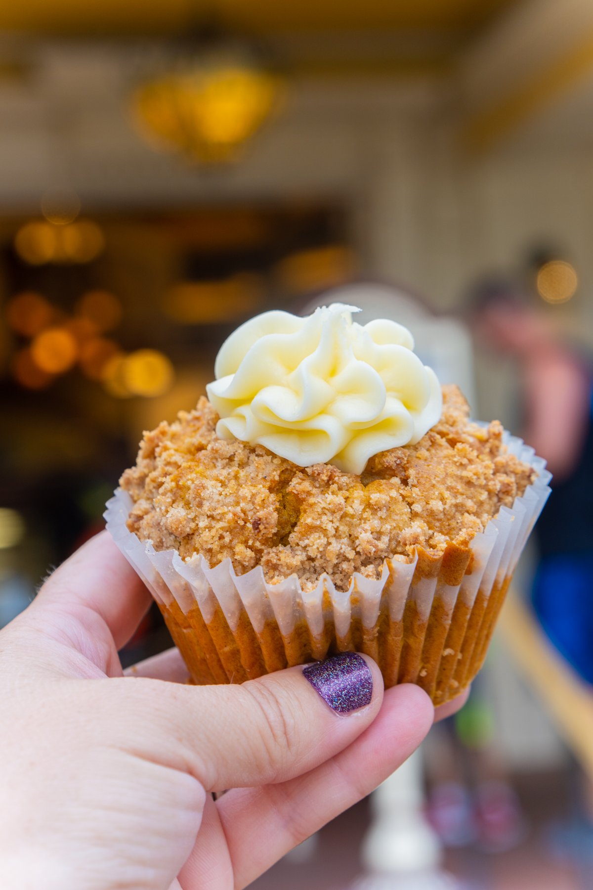 a woman's hand holding a pumpkin muffin at Disneyland