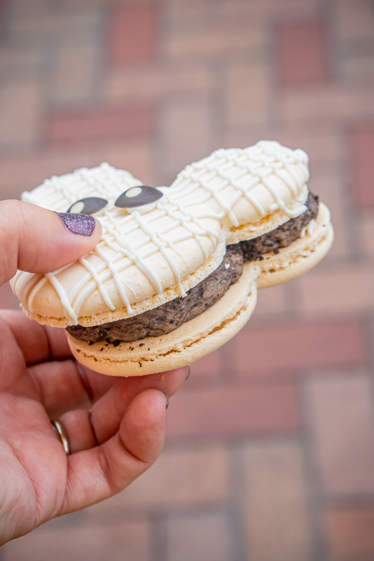 hand holding and showing chocolate filling in Mickey macaron