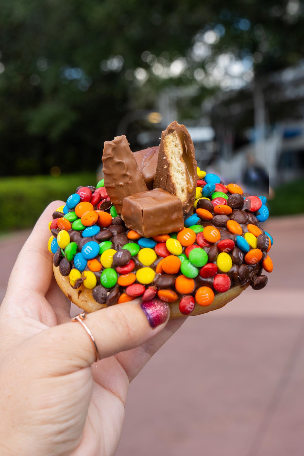 hand holding a donut topped with candy