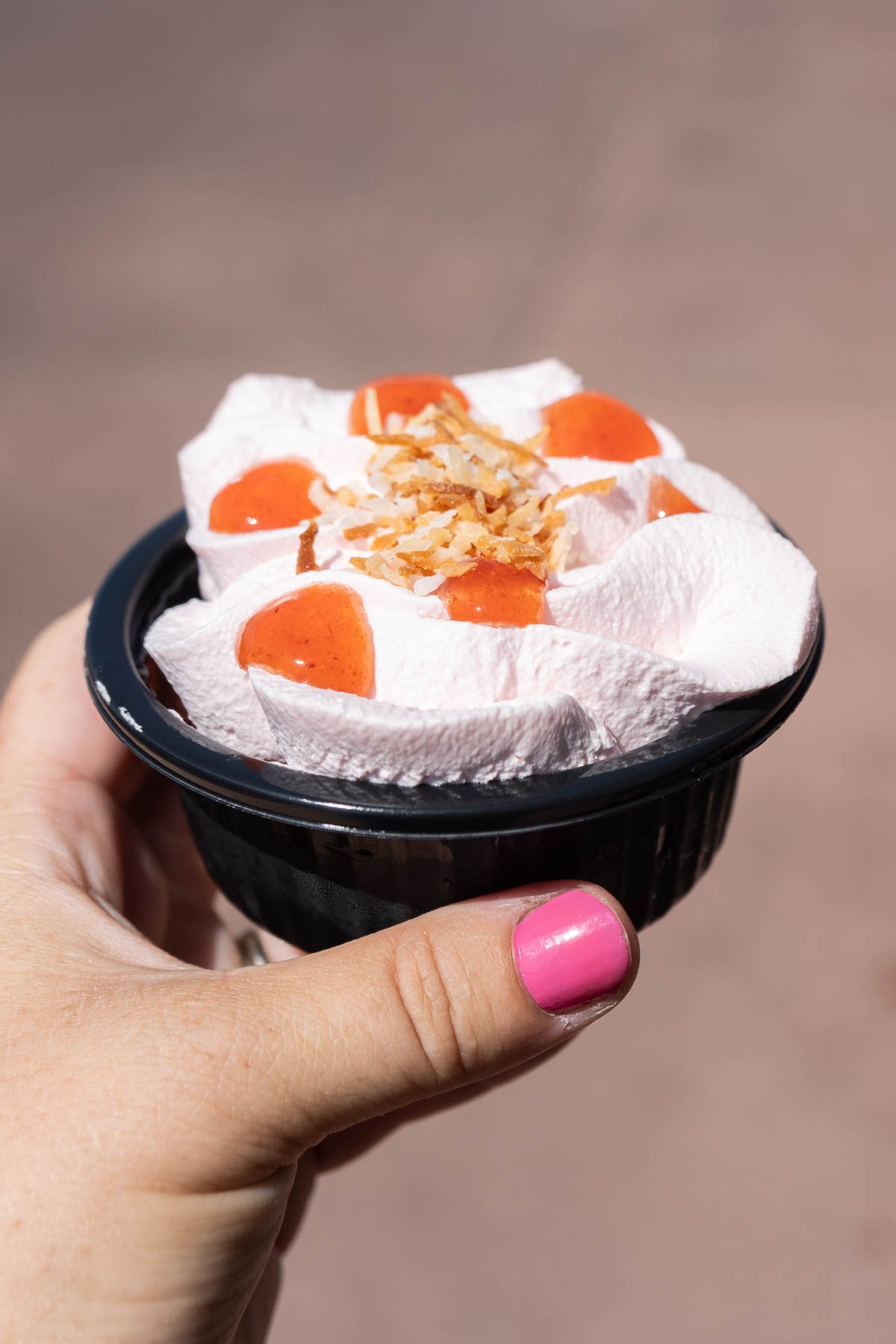 hand holding a guava cake in a black plastic container