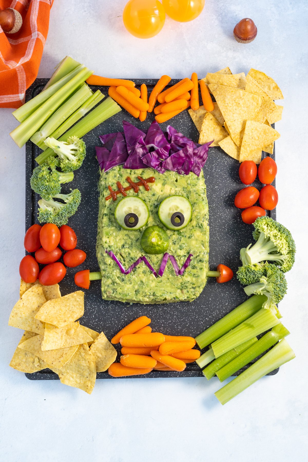 Frankenstein guacamole surrounded by chips, veggies, and more